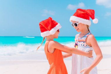 Noel Baba şapkaları birlikte eğleniyor beach Noel tatil sırasında küçük sevimli kız
