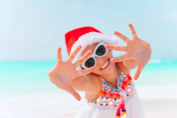 Adorable little girl in Santa hat on tropical beach — Stock Photo, Image