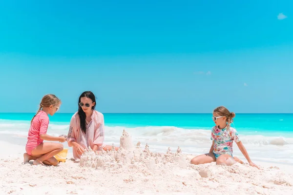 Rodinné provedení hrad z písku na tropické pláži s bílým. Matka a dvě dívky, hrát s pískem na tropické pláži — Stock fotografie