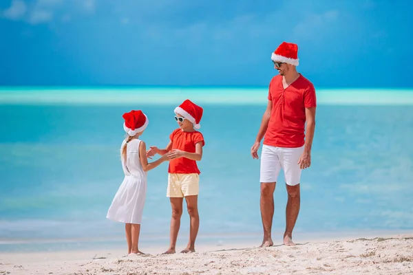 Szczęśliwa rodzina piękne w czerwone kapelusze Santa na tropikalnej plaży na święta — Zdjęcie stockowe