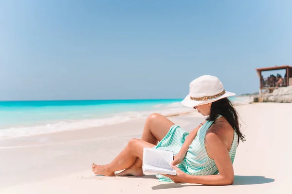 Young woman reading book on chaise-lounge on the beach — Stock Photo, Image