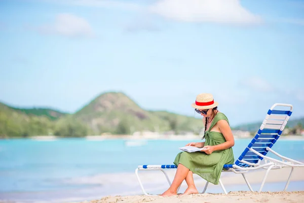 Jonge vrouw lezen boek op chaise-lounge op het strand — Stockfoto