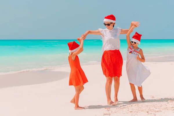 Happy beautiful family in red Santa hats on a tropical beach celebrating Christmas — Stock Photo, Image