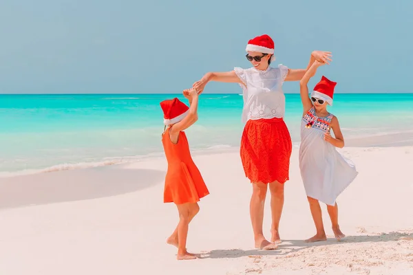 Felice bella famiglia in rosso Santa cappelli su una spiaggia tropicale che celebra il Natale — Foto Stock