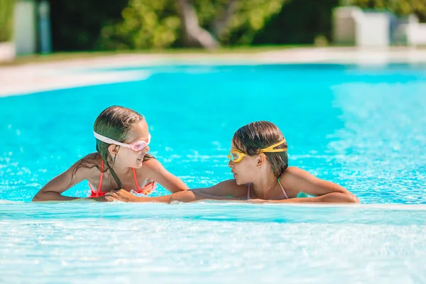 Adorable little girls playing in outdoor swimming pool on vacation — Stock Photo, Image