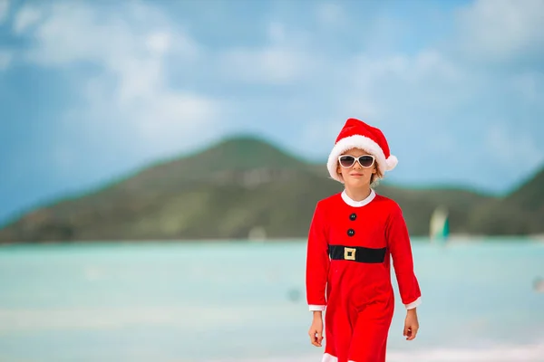 Adorable little girl in Santa hat on tropical beach — Stock Photo, Image