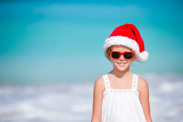 Menina adorável em chapéu de Santa na praia tropical — Fotografia de Stock