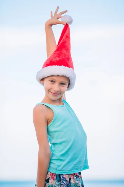Noel Baba şapkası tropik sahilde, sevimli küçük kız — Stok fotoğraf