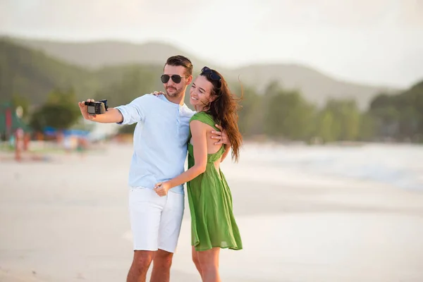 Pareja feliz tomando una foto en la playa blanca en vacaciones de luna de miel — Foto de Stock