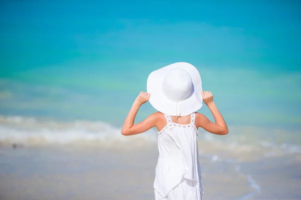 Entzückendes kleines Mädchen mit großem roten Hut am Strand — Stockfoto