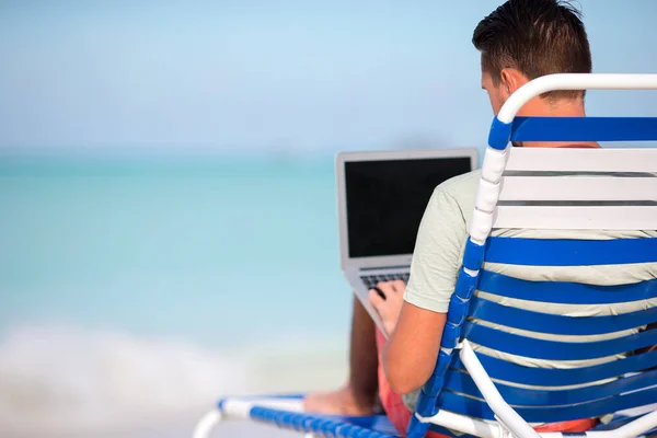 Mladý muž s tabletovým počítačem během dovolené na tropické pláži — Stock fotografie
