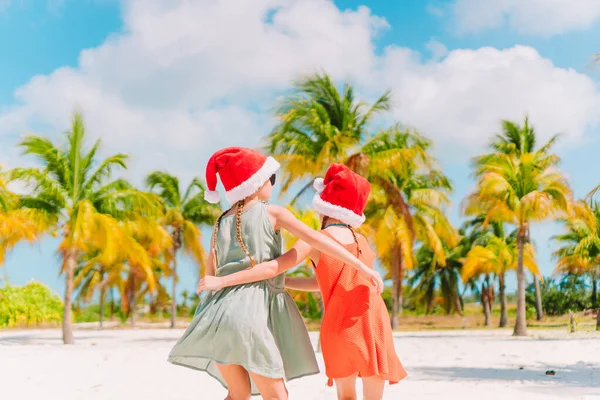 Urocze dziewczynki w Santa kapelusze podczas plaży Christmas vacation wspólna zabawa — Zdjęcie stockowe