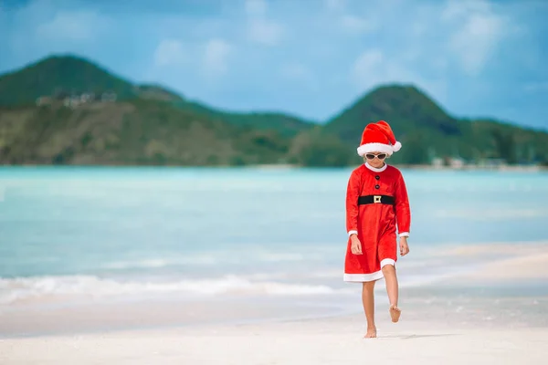 Adorable little girl in Santa hat on tropical beach — Stock Photo, Image