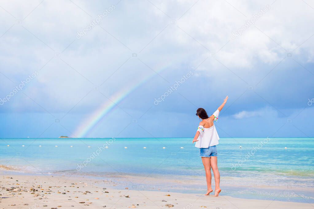 Beautiful happy woman on the beach with beautiful rainbow over the sea