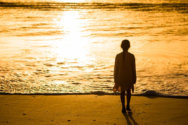 Adorable niña feliz caminando en la playa blanca al atardecer . — Foto de Stock