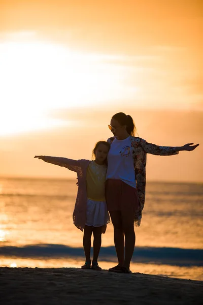 小さな女の子とビーチで夕日にシルエットを幸せな母 — ストック写真