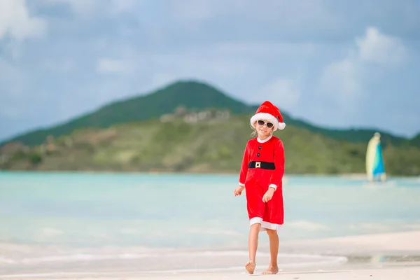 Schattig meisje in Kerstman hoed op tropisch strand — Stockfoto