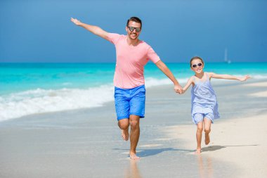 Küçük kız ve mutlu baba kumsal tatili boyunca eğleniyorlar.