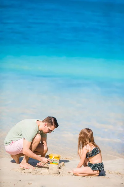Семейный замок из песка на белом пляже. Отец и девочка играют с песком на тропическом пляже — стоковое фото