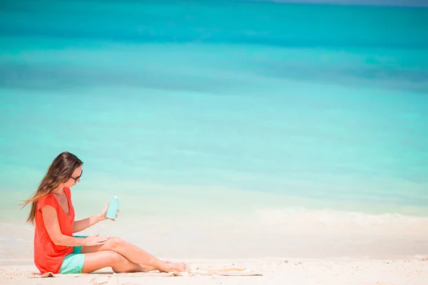 Mooie jonge vrouw met een zonnebrandcrème liggend op tropisch strand — Stockfoto