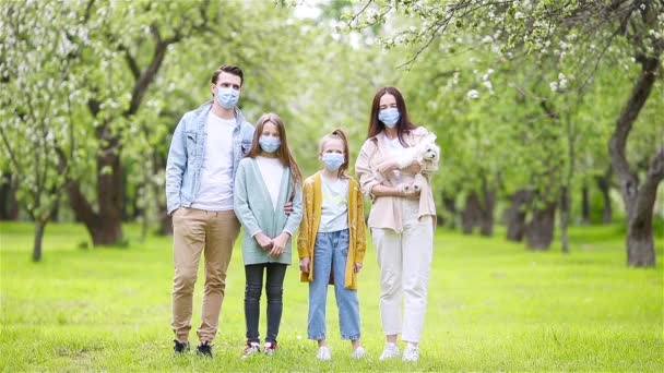 Прекрасная семья в цветущем вишневом саду в масках — стоковое видео