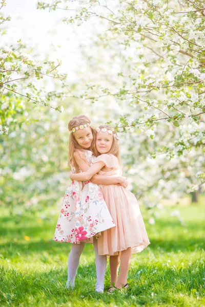 Adorables niñas en el jardín de manzanos en flor en el día de primavera —  Fotos de Stock