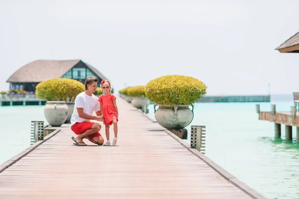 Маленька дівчинка з татом на дерев'яному джинсі біля водного бунгало в екзотичному курорті — стокове фото