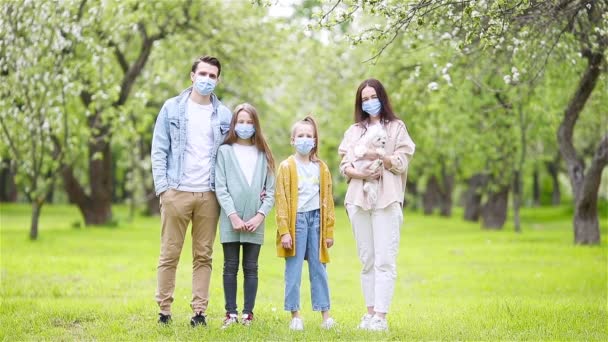 Adorable familia en floreciente jardín de cerezos en máscaras — Vídeos de Stock