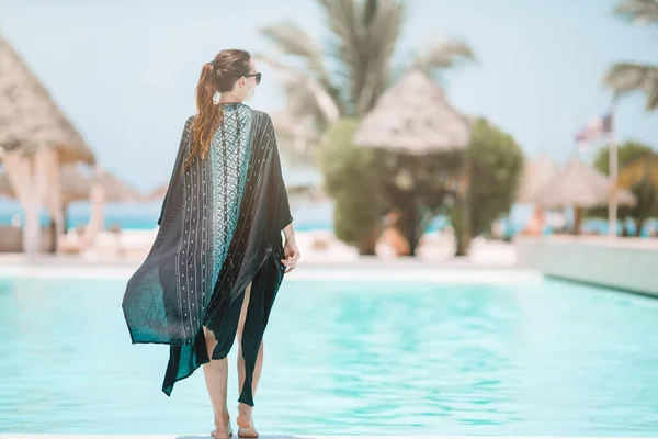 Mulher relaxante na piscina em um resort de hotel de luxo desfrutando de férias perfeitas na praia — Fotografia de Stock