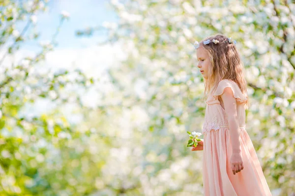 Schattig klein meisje in bloeiende appeltuin op mooie lentedag — Stockfoto