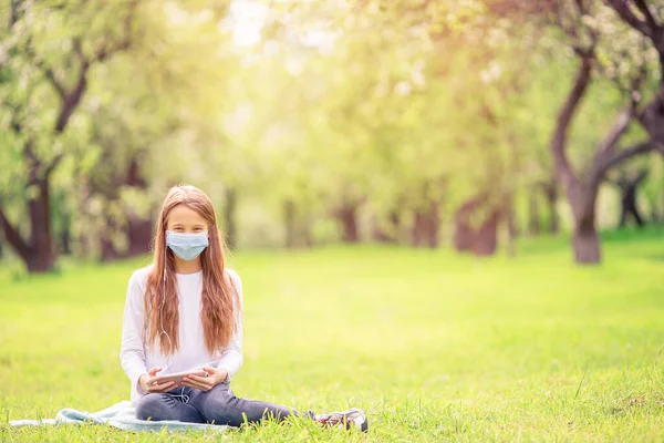 Petite fille avec chien portant un masque médical de protection pour prévenir le virus à l'extérieur dans le parc — Photo