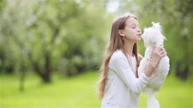 Küçük gülümseyen kızlar parkta oynuyorlar ve yavru köpeklere sarılıyorlar.