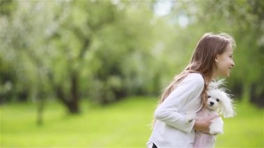 Küçük gülümseyen kızlar parkta oynuyorlar ve yavru köpeklere sarılıyorlar.