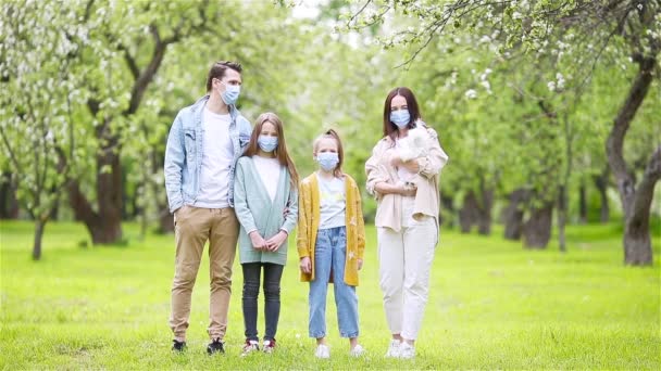 Rozkošná rodina v kvetoucí třešňové zahradě v maskách — Stock video