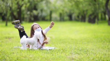 Parkta virüsü önlemek için köpekli küçük bir kız koruyucu maske takıyor.