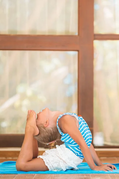 Tropikal plajda yoga yapan sevimli küçük bir kız. — Stok fotoğraf