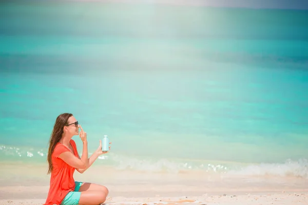 美しいです若いです女性保持A suncream嘘熱帯のビーチ — ストック写真