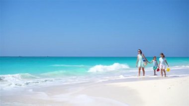 Anne ve çocukların ailesi beyaz sahilde yürüyor.