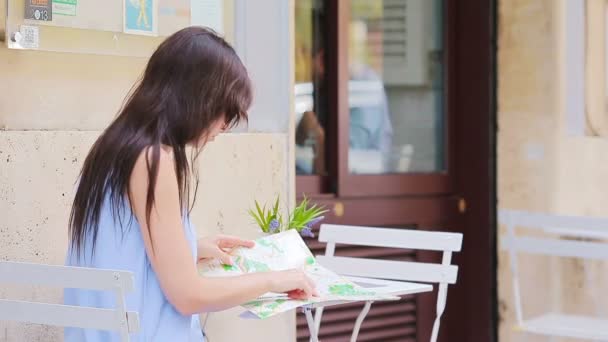 Jeune femme européenne avec carte de la ville dans un café en plein air. Portrait de jeune touriste attrayant à l'heure du déjeuner — Video