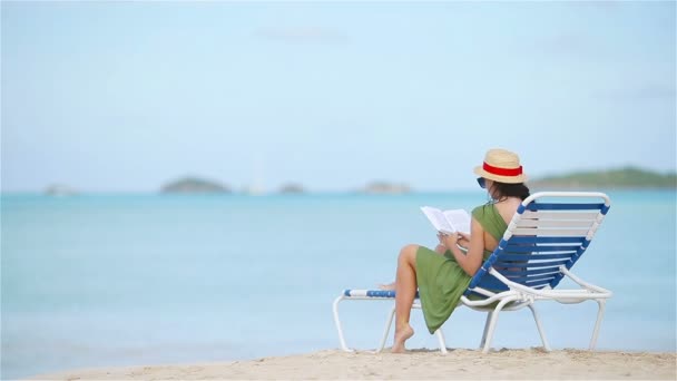 Junge Frau liest Buch am tropischen weißen Strand — Stockvideo