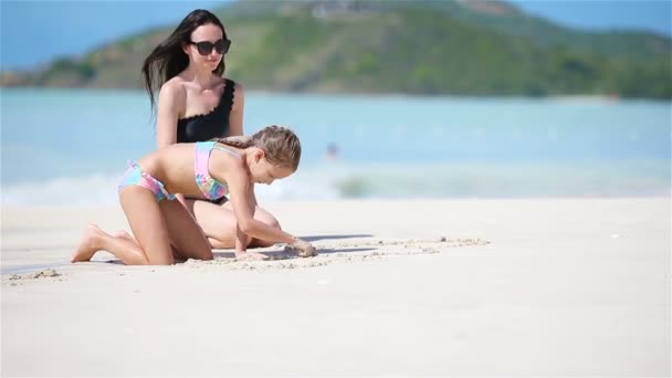 Anya és a kislánya élvezik a karibi tengerparti vakációt. Család játszik homokkal a trópusi strandon — Stock videók