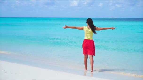 Szczęśliwa dziewczyna na plaży spacerująca po płytkiej wodzie. Filmik o zwolnionym tempie. — Wideo stockowe