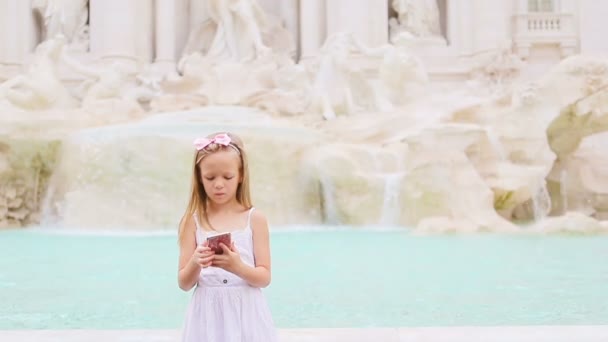 Adorable little girl with smart phone at warm day outdoors in european city near famous Fontana di Trevi — Stock Video