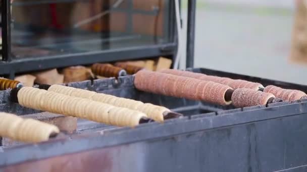 Comida callejera en el mercado de Praga al aire libre. Proceso de fabricación de productos tradicionales de panadería checa trdelnik . — Vídeos de Stock