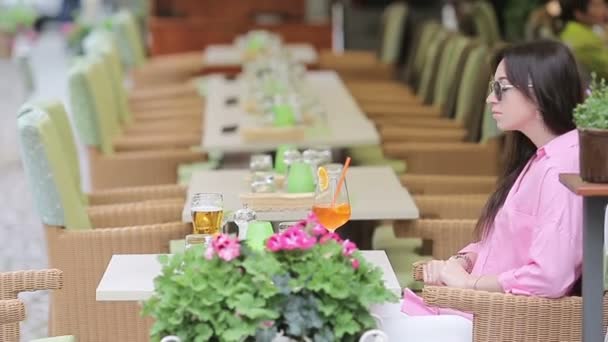 Bir kafede oturmuş lezzetli bir kokteyl içen güzel bir kadının portresi. Open Air RestarAunt 'da Avrupa tatillerinin tadını çıkarın. — Stok video
