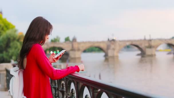 Jovem mulher caucasiana usando seu smartphone ao ar livre fundo famosa ponte . — Vídeo de Stock
