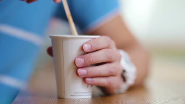 Primer plano de las manos masculinas agitar el azúcar en un vaso con café en la cafetería . — Vídeos de Stock