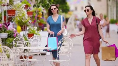 İki moda alışverişi yapan kadın sokakta alışveriş yapıyor. Satış, tüketim ve insan konsepti. Kafkasyalı kızlar açık kafede sıcak günlerinin tadını çıkarırlar..