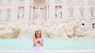 Avrupai 'de, ünlü Fontana di Trevi yakınlarında sıcak bir günde cep telefonu olan sevimli küçük bir kız.