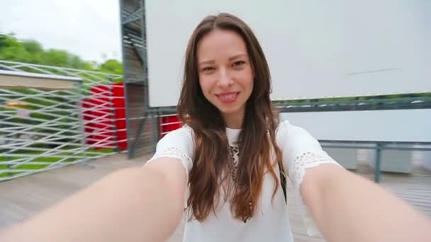 Jong meisje maakt videosselfie en heeft plezier in het park. Lifestyle selfie portret van jonge positieve vrouw hebben plezier en het nemen van selfie. Concept fun met nieuwe trends en technologie. — Stockvideo